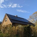 Einfamilienhaus mit moderner Photovoltaikanlage auf dem Dach bei sonnigem Wetter.